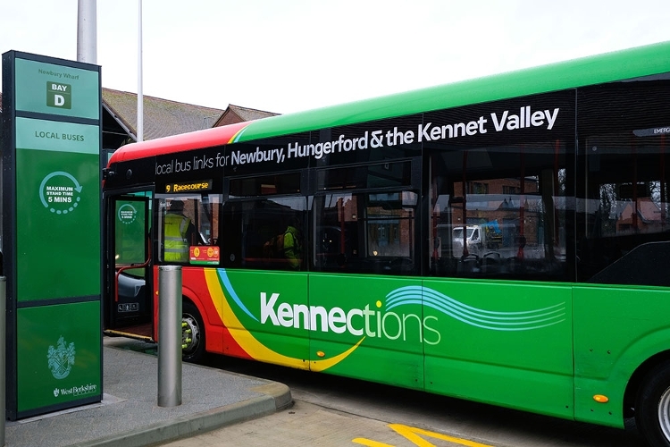 A photograph of a green and red Kennections bus parked at Newbury Wharf Bus Station