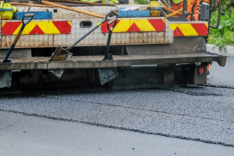 A close up photograph of a vehicle laying tarmac on a road