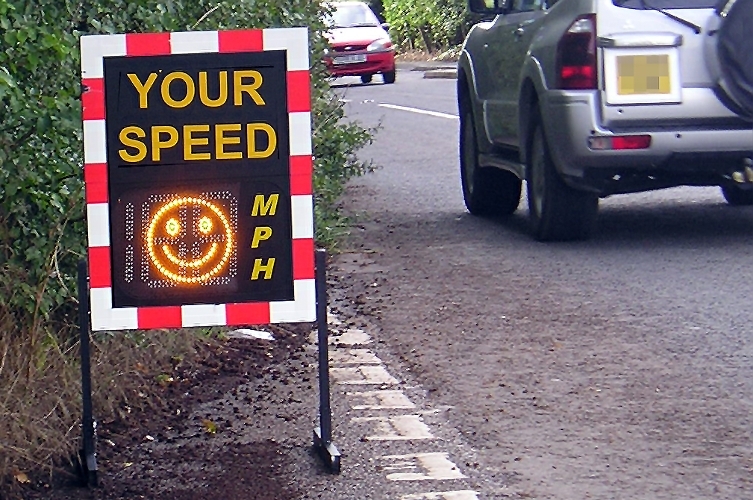 A photograph of a vehicle activated speed sign beside a busy road