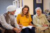 A woman sitting on the sofa with her mum and dad. They are all looking at a booklet.