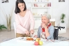 A young woman supporting elderly woman with preparing a meal.
